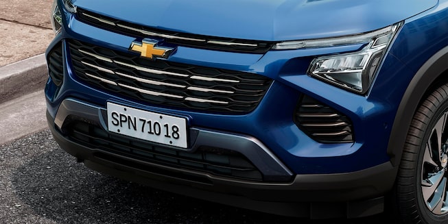 Imagem do novo Chevrolet Spin, na cor Azul Boreal, com foco nos faróis em LED, e na grade frontal com detalhes cromados.