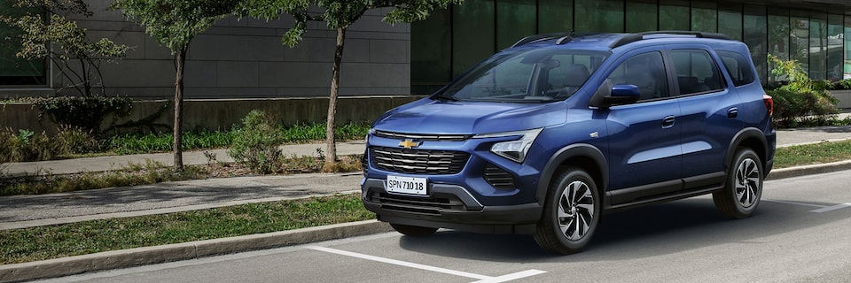 Novo SUV Chevrolet SPIN 2025, na cor azul, andando por rua residencial.