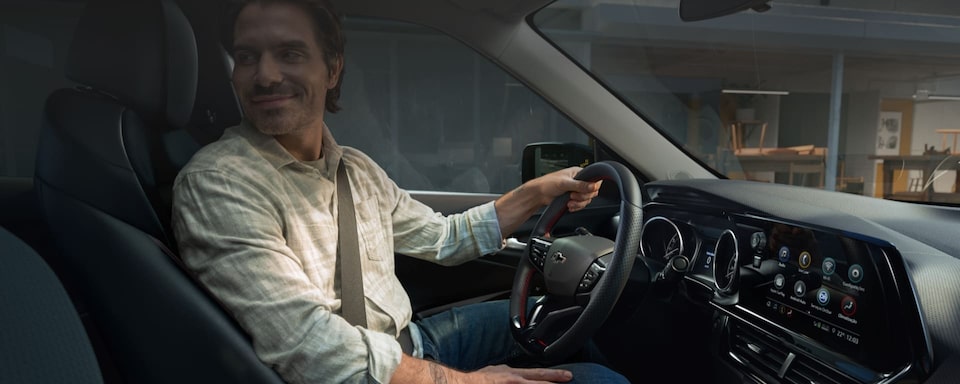 Imagem mostrando um homem, branco, de meia idade, usando óculos, no interior de um Chevrolet, olhando para o banco trazeiro, como se estivesse observando alguém. Arte chamando o financiamento de um Chevrolet zero quilômetro.