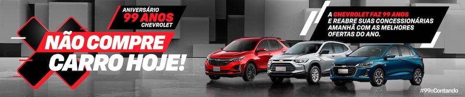 Três carros Chevrolet (vermelho, branco e azul) em um showroom com um banner comemorando o 99º aniversário da Chevrolet. O texto em português desaconselha a compra de um carro hoje, sugerindo melhores negócios amanhã.