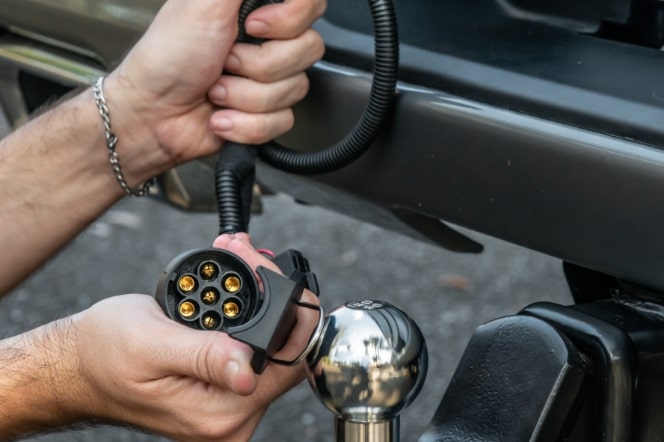 Imagem mostrando as mão de um homem instalando o acessório "adaptador de engate", na traseira da nova picape Chevrolet Silverado.