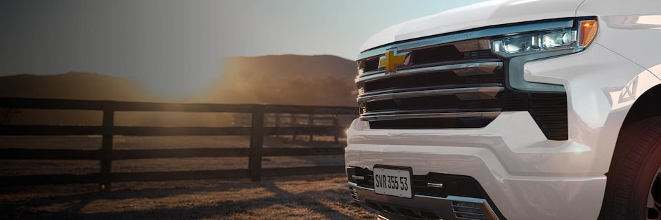 Imagem da frente da nova picape Chevrolet Silverado, branco summit, em estradada rural.